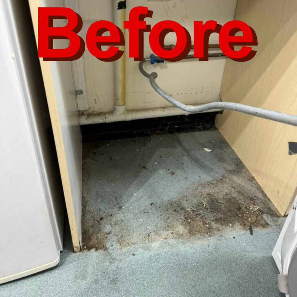 Underneath a washing machine the floor is dirty and stained